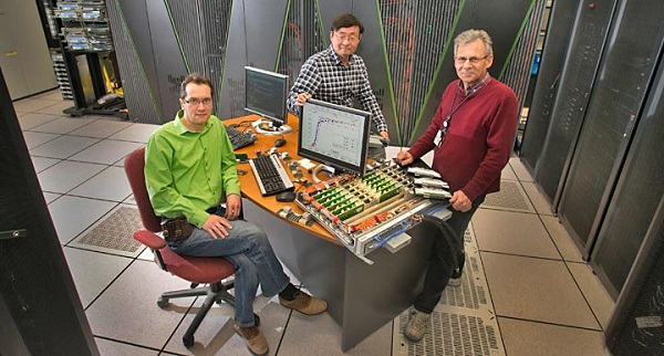 Brookhaven Lab physicists Peter Petreczky and Chulwoo Jung with technology architect Joseph DePace—who oversees operations and maintenance of the Lab's supercomputers—in front of the Blue Gene/Q supercomputer.