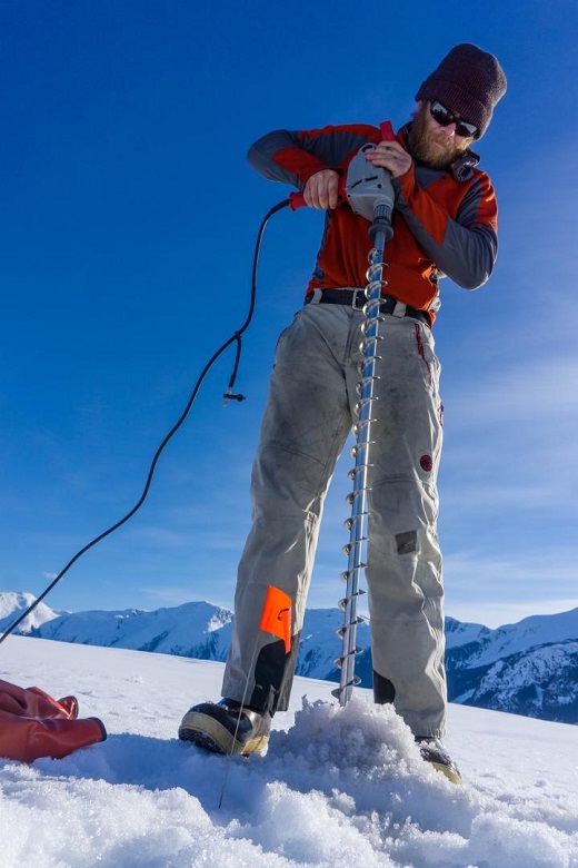 CAPTION Martin Truffer drills holes for explosives in the surface of Taku Glacier. The explosions produce seismic waves that bounce off the sediment below the glacier, providing information about its thickness and character. CREDIT Photo courtesy of Douglas Brinkerhoff