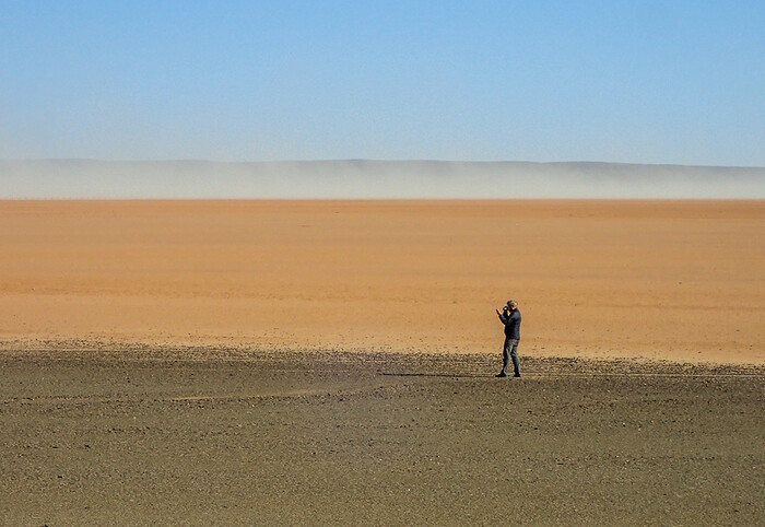 Brian Stewart surveying the extensive scatters of stone artefacts observed along the margin of a now-dry lakebed near Swartkolkvloer.  CREDIT Brian Chase