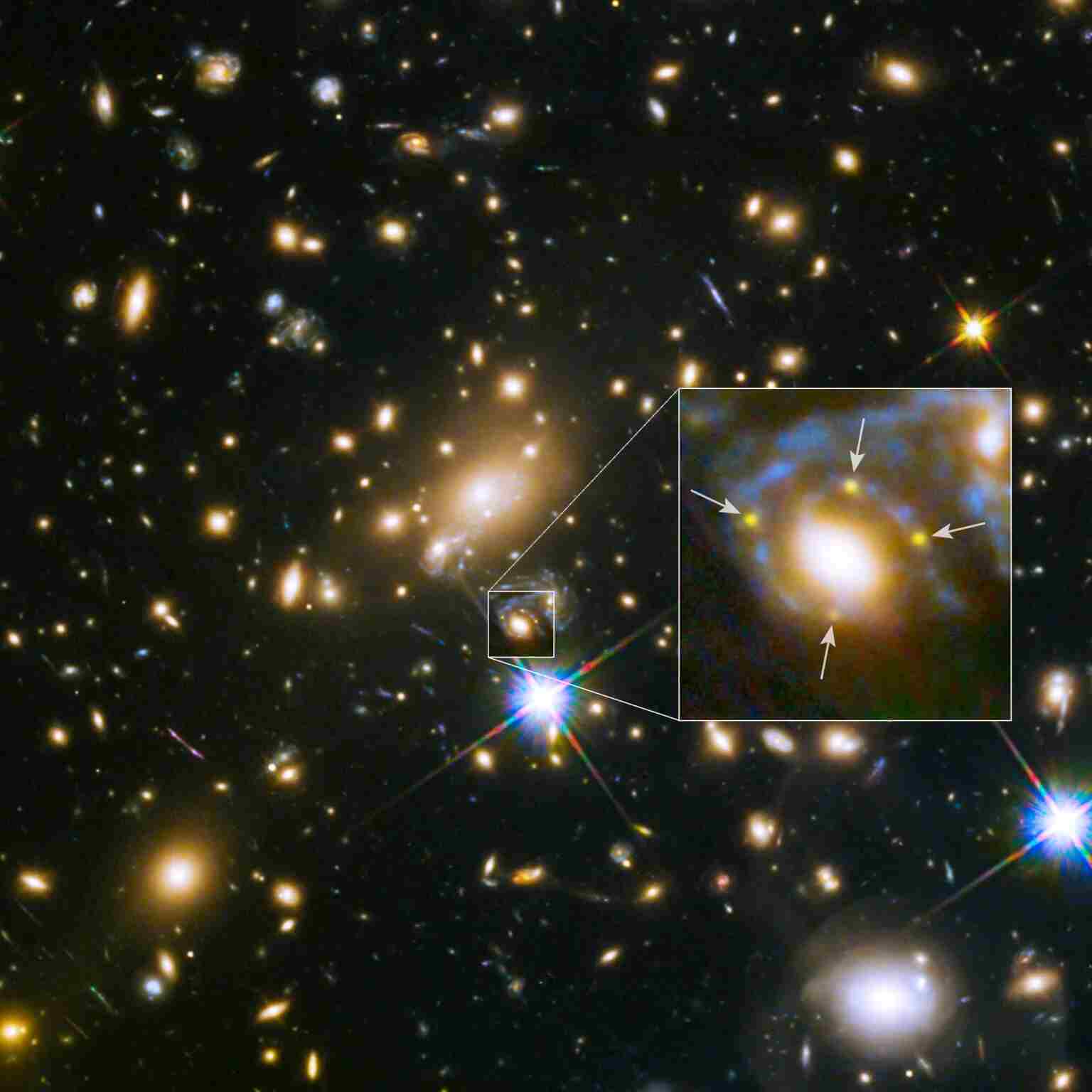 This image, captured by the Hubble Space Telescope, displays a galaxy's powerful gravity embedded in a massive cluster of galaxies that forms multiple images of a single distant supernova behind it. The galaxy lies within a large cluster of galaxies called MACS  J1149.6+2223, which is more than 5 billion light-years away from Earth. In the zoomed-in view of the galaxy, the multiple copies of an exploding star named Supernova Refsdal are indicated by arrows. This supernova is located 9.3 billion light-years away from Earth. The image credit goes to NASA, ESA, and S. Rodney (JHU) and the FrontierSN team; T. Treu (UCLA), P. Kelly (UC Berkeley), and the GLASS team; J. Lotz (STScI) and the Frontier Fields team; M. Postman (STScI) and the CLASH team; and Z. Levay (STScI).