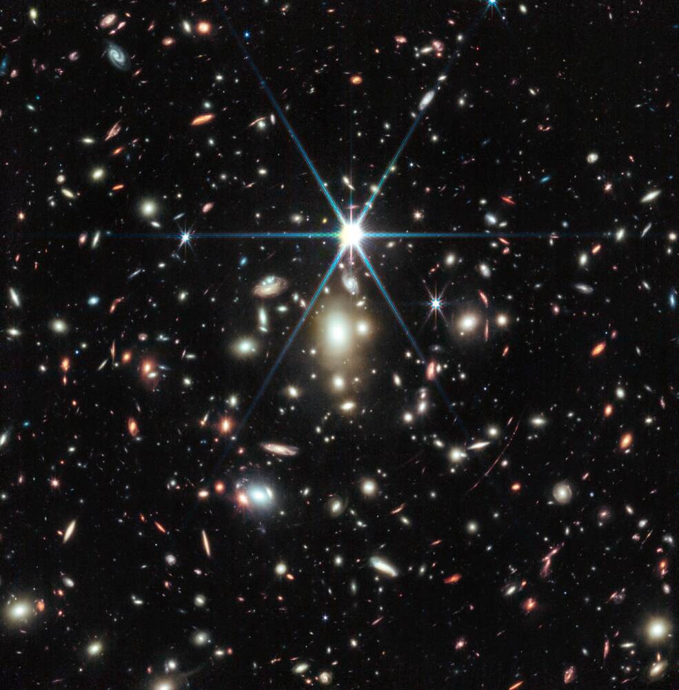 This image from NASA’s James Webb Space Telescope of a massive galaxy cluster called WHL0137-08 contains the most strongly magnified galaxy known in the universe’s first billion years: the Sunrise Arc, and within that galaxy, the most distant star ever detected. In this image, the Sunrise Arc appears as a red streak just below the diffraction spike at the 5 o’clock position. Credits: Image: NASA, ESA, CSA, D. Coe (STScI/AURA for ESA; Johns Hopkins University), B. Welch (NASA’s Goddard Space Flight Center; University of Maryland, College Park). Image processing: Z. Levay.