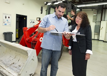 Purdue University professor Monika Ivantysynova and doctoral student Naseem Daher discuss research related to a new hydraulic-steering technology, while graduate student Michael Sprengel looks over the electronic controls of a front loader. Researchers led by Ivantysynova, the Maha Fluid Power Systems Professor, have shown how to reduce fuel consumption while dramatically improving the efficiency of hydraulic steering systems in heavy construction equipment. (Purdue University photo/Mark Simons) Purdue's thermodynamic modeling steers tech to save fuel, ups efficiency