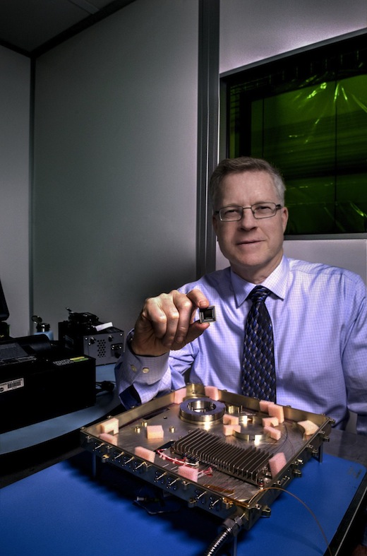 CAPTION NASA laser expert Mike Krainak and his team plan to replace portions of this fiber-optic receiver with an integrated-photonic circuit, whose size will be similar to the chip he is holding. The team then plans to test the advanced modem on the International Space Station. CREDIT Credits: NASA/W. Hrybyk
