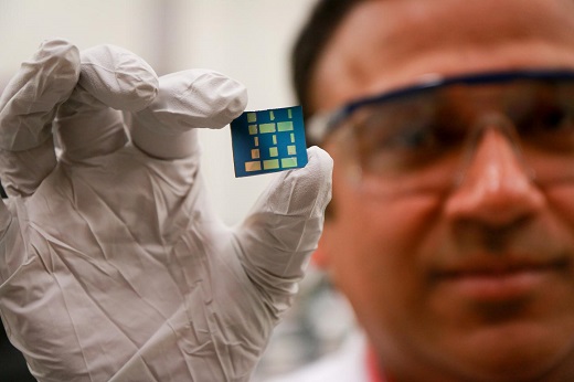 CAPTION University of Utah materials science and engineering associate professor Ashutosh Tiwari holds up a substrate layered with a newly discovered 2-D material made of tin and oxygen. Tiwari and his team have discovered this new material, tin monoxide, which allows electrical charges to move through it much faster than common 3-D material such as silicon. This breakthrough in semiconductor material could lead to much faster computers and mobile devices such as smartphones that also run on less power and with less heat. CREDIT Dan Hixson/University of Utah College of Engineering CAPTION University of Utah materials science and engineering associate professor Ashutosh Tiwari holds up a substrate layered with a newly discovered 2-D material made of tin and oxygen. Tiwari and his team have discovered this new material, tin monoxide, which allows electrical charges to move through it much faster than common 3-D material such as silicon. This breakthrough in semiconductor material could lead to much faster computers and mobile devices such as smartphones that also run on less power and with less heat. CREDIT Dan Hixson/University of Utah College of Engineering