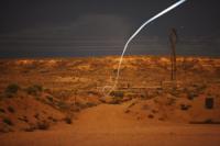 A tiny light-emitting diode, or LED, attached to a self-guided bullet at Sandia National Laboratories shows a bright path during a nighttime field test that proved the battery and electronics could survive the bullet's launch.
