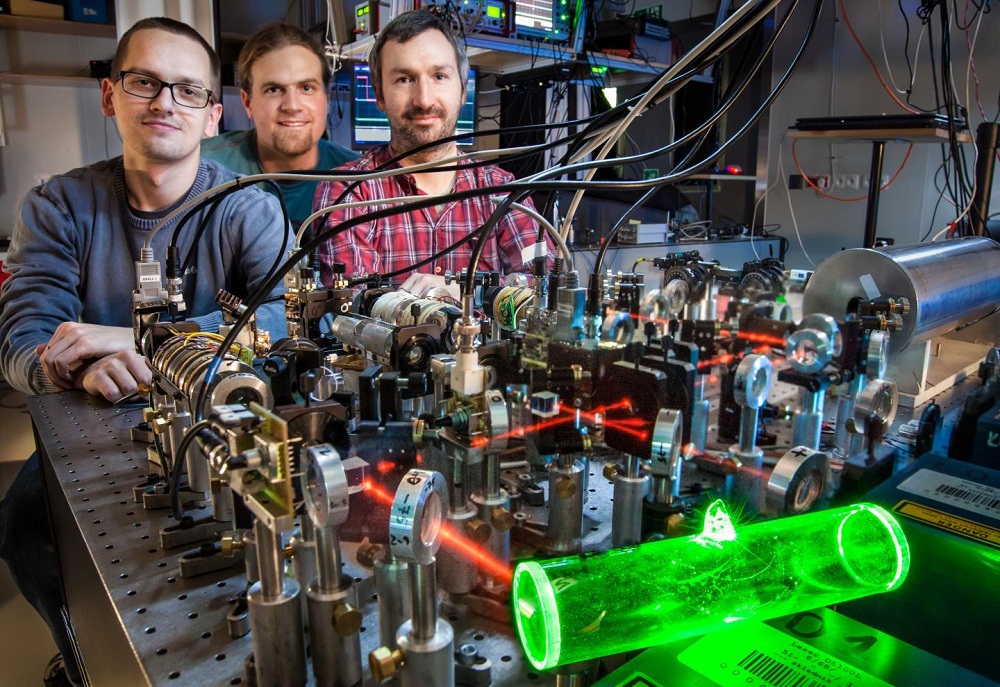 An atomic memory (glowing green), made at the Faculty of Physics at the University of Warsaw, can be used to store quantum information in telecomunication purposes. From left to right: Michał Dąbrowski, Radek Chrapkiewicz and Wojciech Wasilewski. Credit: ©FUW, R. Chrapkiewicz An atomic memory (glowing green), made at the Faculty of Physics at the University of Warsaw, can be used to store quantum information in telecomunication purposes. From left to right: Michał Dąbrowski, Radek Chrapkiewicz and Wojciech Wasilewski. Credit: ©FUW, R. Chrapkiewicz