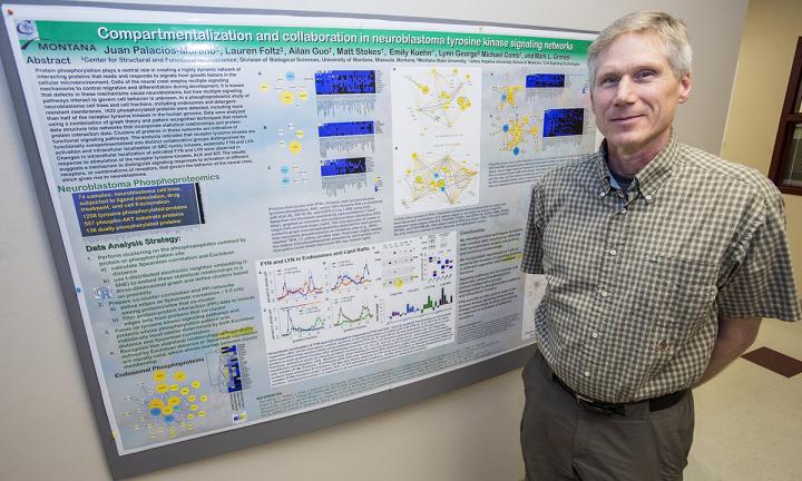 CAPTION UM cell biologist Mark Grimes stands in front of a poster displaying the findings in his research paper. CREDIT Todd Goodrich CAPTION UM cell biologist Mark Grimes stands in front of a poster displaying the findings in his research paper. CREDIT Todd Goodrich