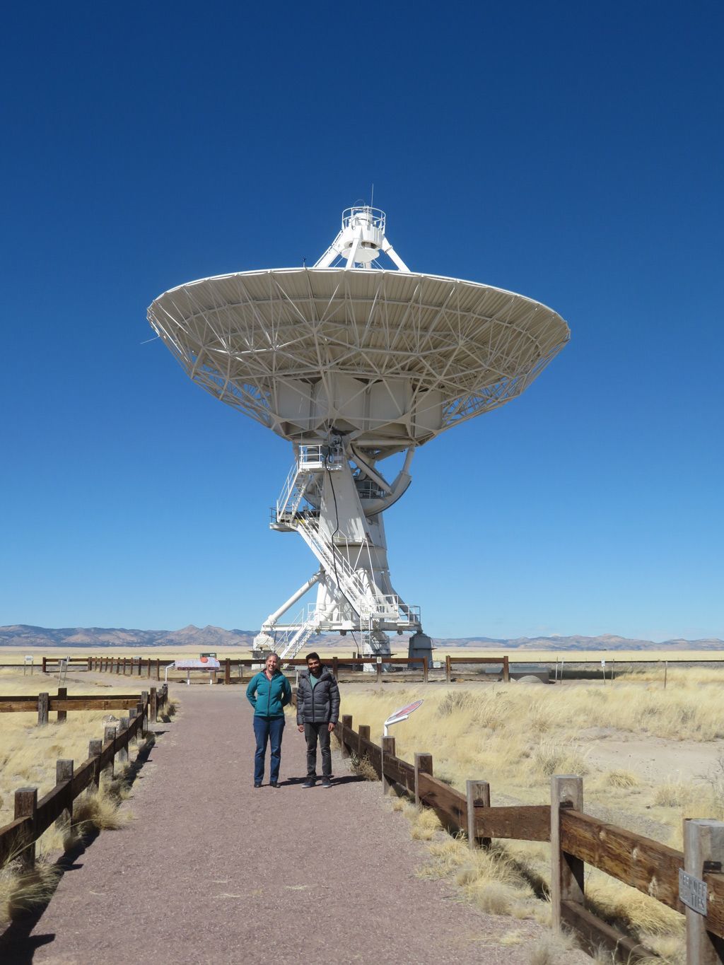 SETI Institute Post-Doctoral Researchers, Dr Savin Varghese and Dr Chenoa Tremblay, in front of one of the 82-foot diameter dishes that makes up the Very Large Array.