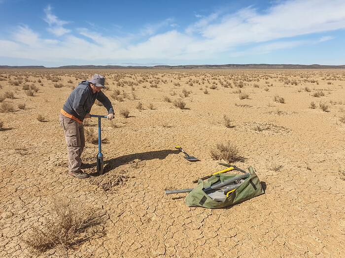 Andrew Carr collecting sediment samples dating to the Last Glacial Maximum from the dry lakebed at Swartkolkvloer.  CREDIT Brian Chase