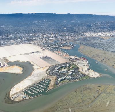 An aerial view of the San Mateo County coastline shows a healthy marsh in the foreground, salt ponds being considered for restoration in the middle left, the Google campus at the center, a marsh being actively restored in the back right, and the port of Redwood City.